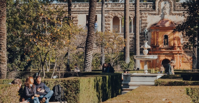 Люди отдыхают в саду Алькасаре в солнечный зимний день. Севилья, Испания